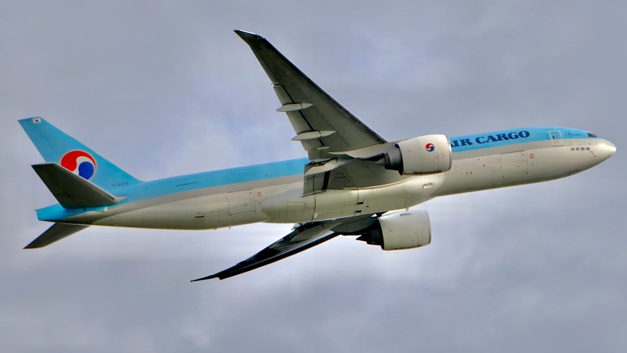 A cargo airplane flying against a backdrop of cloudy skies, illustrating global logistics.
